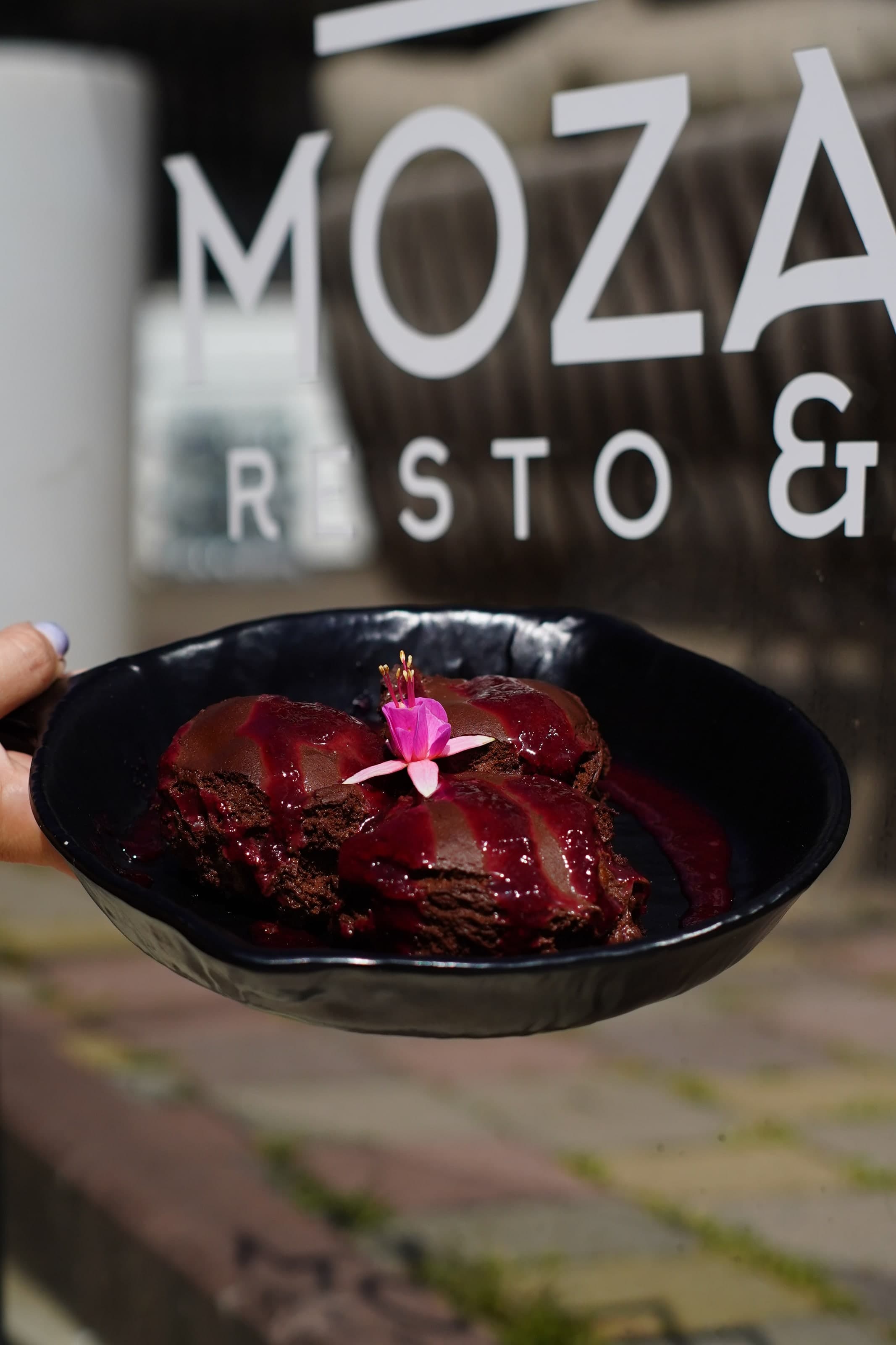 Десерт у чорній мисці на тлі вивіски Mozart Resto